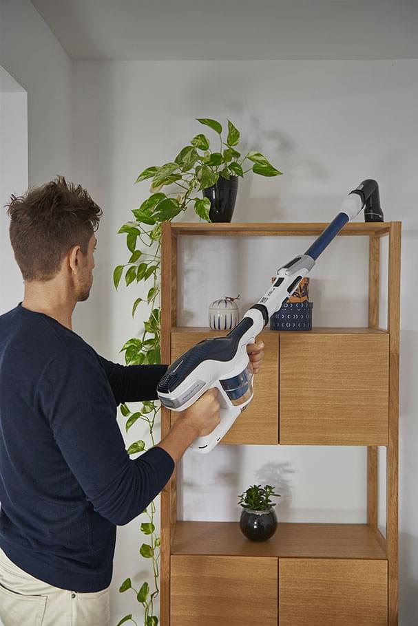 Man vacuuming above a piece of furniture