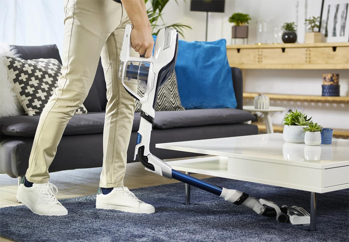 Man vacuuming under a white table